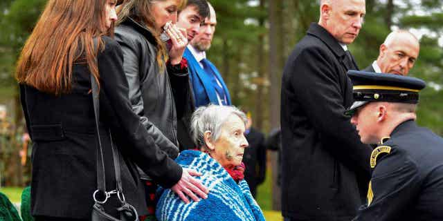 Patricia Lyons, middle, the only remaining sibling of U.S. Army Sgt. Alfred Sidney, is handed the American flag from his burial service in Littleton, New Hampshire, on Dec. 8, 2022. The remains of Sidney, who went missing during the Korean War and was later reported to have died in a prisoner of war camp, were recently identified, and his body was buried.