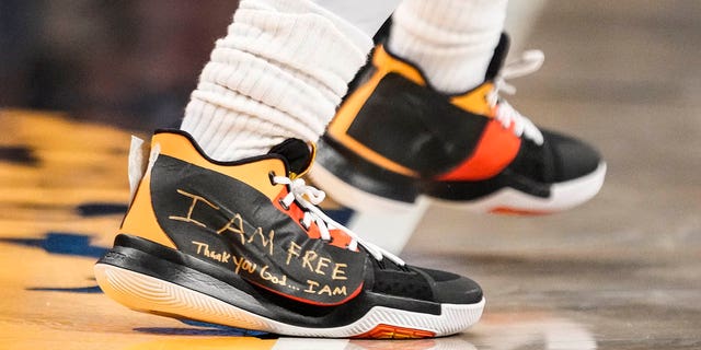 Brooklyn Nets guard Kyrie Irving, #11, wears sneakers with logos covered in tape with the words "I AM FREE Thank you God … I AM" written in gold colored marker during the second half of an NBA basketball game against the Charlotte Hornets, Wednesday, Dec. 7, 2022, in New York. 