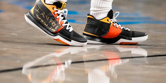Brooklyn Nets guard Kyrie Irving, #11, wears sneakers with logos covered in tape with the words "I AM FREE Thank you God … I AM" written in gold colored marker during the second half of an NBA basketball game against the Charlotte Hornets, Wednesday, Dec. 7, 2022, in New York. 