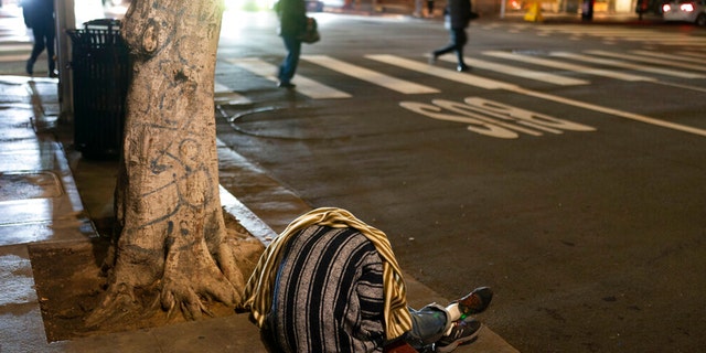 A homeless person sleeps on a sidewalk in Los Angeles, Wednesday, Dec. 14, 2022.