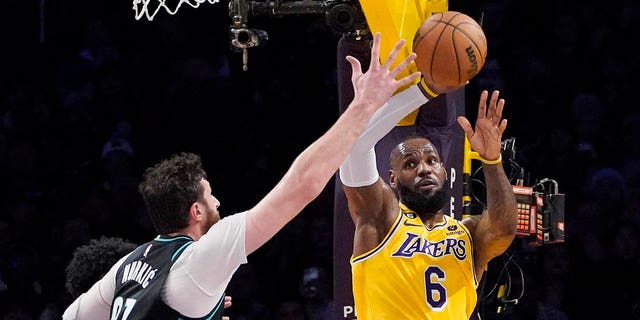 Los Angeles Lakers forward LeBron James, right, passes the ball while under pressure from Portland Trail Blazers center Jusuf Nurkic during the second half of an NBA basketball game Wednesday, Nov. 30, 2022, in Los Angeles.