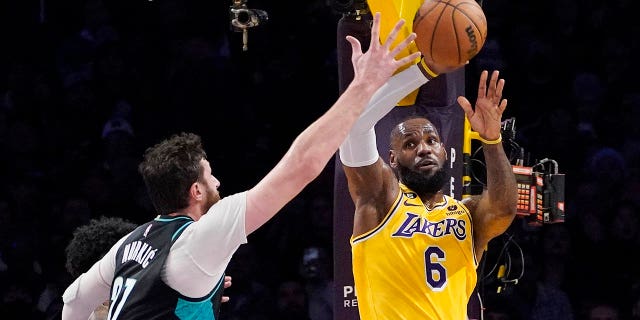 Los Angeles Lakers forward LeBron James, right, passes the ball while under pressure from Portland Trail Blazers center Jusuf Nurkic during the second half of an NBA basketball game Wednesday, Nov. 30, 2022, in Los Angeles.