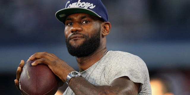 El jugador de la NBA LeBron James del Miami Heat patea una pelota de fútbol en el AT&T Stadium antes del partido del domingo por la noche entre los New York Giants y los Dallas Cowboys el 8 de septiembre de 2013 en Arlington, Texas.