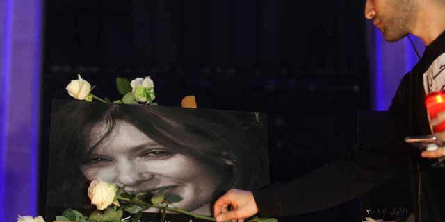 A Lebanese activist places a flower on the poster of Rebecca Dykes, a British woman killed by an Uber driver, during a candlelight vigil to condemn violence against women in Beirut, Lebanon December 23, 2017.