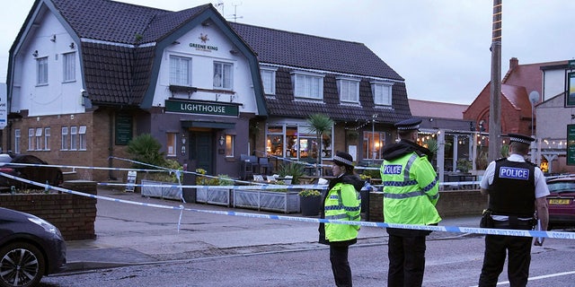 Police officers stand on duty at the Lighthouse Inn in Wallasey Village, near Liverpool, England, Sunday, Dec. 25, 2022. A Christmas Eve shooting at a pub in northwest England killed a young woman and wounded three men, police said Sunday. The Merseyside Police force said it was investigating the 11:50 p.m. Saturday shooting at the Lighthouse pub in the town of Wallasey as a murder case. Police have not detained any suspects. (Peter Byrne/PA via AP)