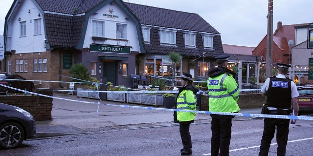 Police officers stand on duty at the Lighthouse Inn in Wallasey Village, near Liverpool, England, Sunday, Dec. 25, 2022. A Christmas Eve shooting at a pub in northwest England killed a young woman and wounded three men, police said Sunday. The Merseyside Police force said it was investigating the 11:50 p.m. Saturday shooting at the Lighthouse pub in the town of Wallasey as a murder case. Police have not detained any suspects. (Peter Byrne/PA via AP)