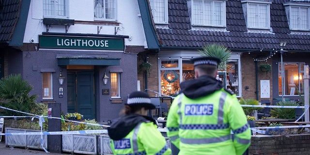 Police officers stand on duty at the Lighthouse Inn in Wallasey Village, near Liverpool, England, Sunday, Dec. 25, 2022. A Christmas Eve shooting at a pub in northwest England killed a young woman and wounded three men, police said Sunday. The Merseyside Police force said it was investigating the 11:50 p.m. Saturday shooting at the Lighthouse pub in the town of Wallasey as a murder case. Police have not detained any suspects. (Peter Byrne/PA via AP)