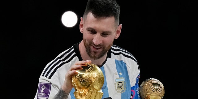 Argentina's Lionel Messi pats the trophy after winning the World Cup final soccer match between Argentina and France at Lusail Stadium in Lusail, Qatar, Sunday, Dec. 18, 2022.