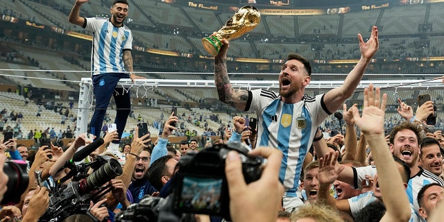 Argentina's Lionel Messi celebrates with the trophy in front of the fans after winning the World Cup final match against France at the Lusail Stadium in Lusail, Qatar, Sunday, Dec. 18, 2022.