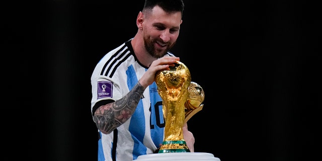 Lionel Messi touches the World Cup trophy