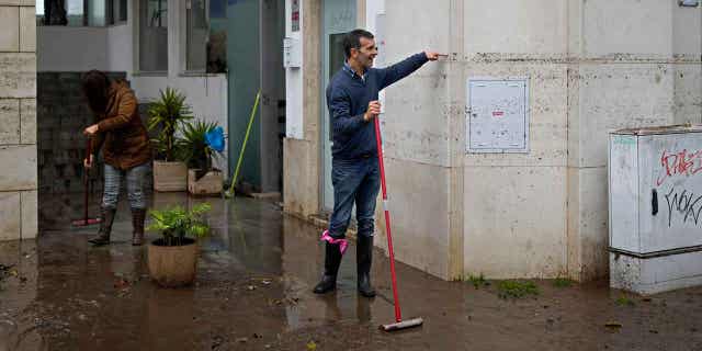 A man sweeping water from a building shows the height reached by the water when the street was flooded overnight in Alges, Portugal on December 13, 2022.