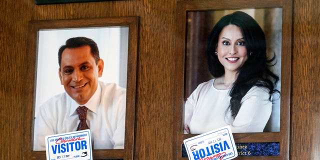 Stickers are placed over the photos of Los Angeles council members Gil Cedillo, left, and Nury Martinez near the entrance to the John Ferraro Council Chambers on October 12, 2022 in Los Angeles. 