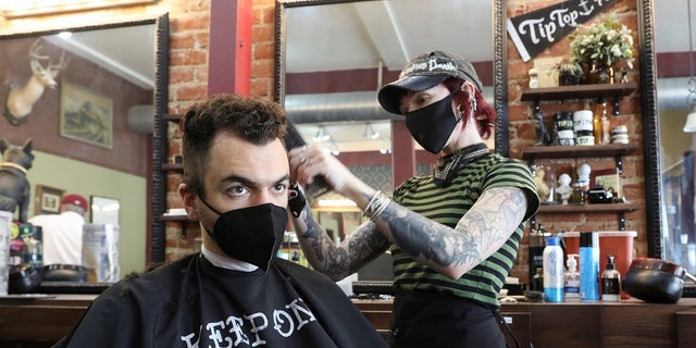 A man gets a haircut as people still wear their masks, amid the coronavirus pandemic, in Los Angeles in February. Los Angeles County health officials on Thursday said they could reimpose the mandate if COVID transmission climbs. 