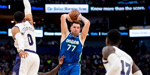 Dallas Mavericks guard Luka Doncic (77) prepares to pass the ball as Los Angeles Lakers guard Russell Westbrook (0) and Los Angeles Lakers guard Dennis Schroder (17) defend him in the second half of an NBA basketball game in Dallas, Sunday, Dec. 25, 2022. 