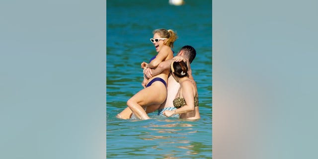 Justin Verlander appears to surprise Kate Upton as he grabs her to toss her in the water. 