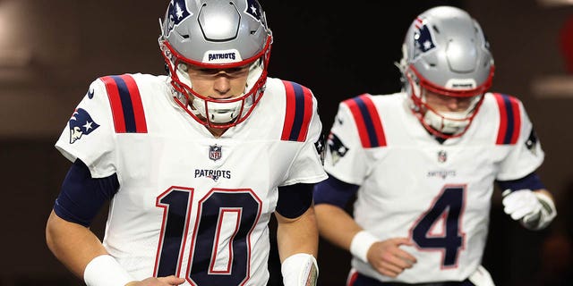 Mac Jones #10 and Bailey Zappe #4 of the New England Patriots take the field prior to the game against the Arizona Cardinals at State Farm Stadium on December 12, 2022 in Glendale, Arizona.