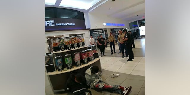 Two suspected robbers sit on the floor after they were taken down by Marine recruiters and bystanders following a smash and grab robbery inside a California shopping mall.