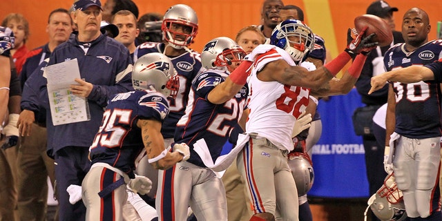 New York Giants wide receiver Mario Manningham (82) makes a catch defended by New England Patriots free safety Patrick Chung (25) and New England Patriots free safety Sterling Moore (29) as the Patriots take on the Giants at Super Bowl XLVI at Lucas Oil Stadium in Indianapolis, IN.