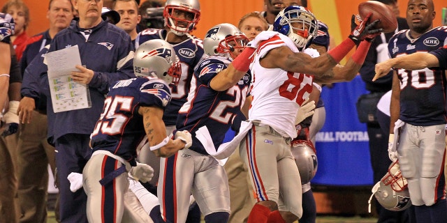 New York Giants wide receiver Mario Manningham (82) makes a catch defended by New England Patriots free safety Patrick Chung (25) and New England Patriots free safety Sterling Moore (29) as the Patriots take on the Giants at Super Bowl XLVI at Lucas Oil Stadium in Indianapolis, IN.
