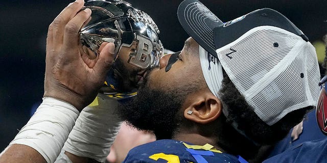 Michigan linebacker Michael Barrett kisses the trophy as he celebrates with teammates after defeating Purdue in the Big Ten championship game, Sunday, Dec. 4, 2022, in Indianapolis.