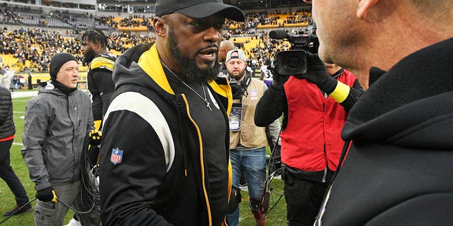 Pittsburgh Steelers head coach Mike Tomlin, center, meets Baltimore Ravens head coach John Harbaugh on the field following an NFL football game in Pittsburgh, Sunday, Dec. 11, 2022. 