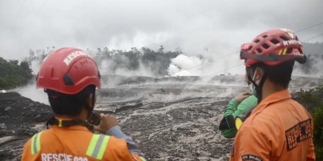 Rescuers monitor the flow of volcanic materials from the eruption of Mount Semeru, in Lumajang, East Java, Indonesia, Sunday, Dec. 4, 2022. Indonesia's highest volcano on its most densely populated island released searing gas clouds and rivers of lava Sunday in its latest eruption. 