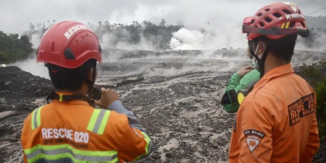 Rescuers monitor the flow of volcanic materials from the eruption of Mount Semeru, in Lumajang, East Java, Indonesia, Sunday, Dec. 4, 2022. Indonesia's highest volcano on its most densely populated island released searing gas clouds and rivers of lava Sunday in its latest eruption. 