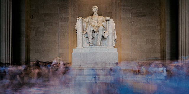 A long camera exposure blurs the crowd of tourists gathered inside the Lincoln Memorial in Washington, D.C.