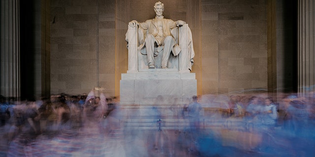 A long camera exposure blurs the crowd of tourists gathered inside the Lincoln Memorial in Washington, D.C.