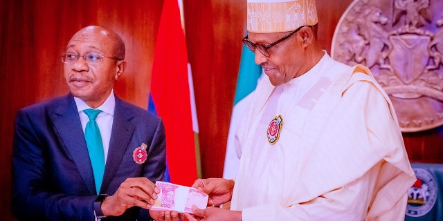 DATULS: Godvins Emifīls, pa kreisi, Nigērijas Centrālās bankas (CBN) prezidents, apmeklē jauno banknošu prezentāciju pēc tam, kad Nigērijas prezidents Muhammadu Buhari, pa labi, atklāja jaunā dizaina banknotes viltošanas un pieaugošo drošības problēmu dēļ 2022. gada 23. novembrī. , Abudžā, Nigērijā.