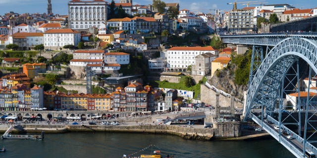 Rabelo port wine barge and The Ponte de Dom Luis I - metal arch bridge over River Douro connecting Porto to V|la Nova de Gaia, Portugal.
