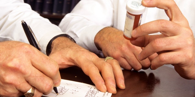 A doctor writes a refill prescription