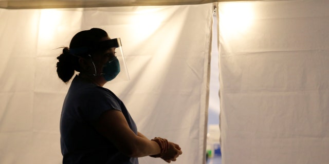 Nurse Jess White stands outside a tent set up to create a drive-through testing clinic for coronavirus, flu and RSV, currently by appointment for employees at UW Medical Center Northwest in Seattle, March 9, 2020.