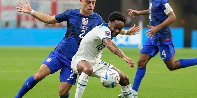 Sergino Dest of the United States, left, challenges for the ball with England's Raheem Sterling during the World Cup group B soccer match between England and The United States, at the Al Bayt Stadium in Al Khor, Qatar, Friday, Nov. 25, 2022.