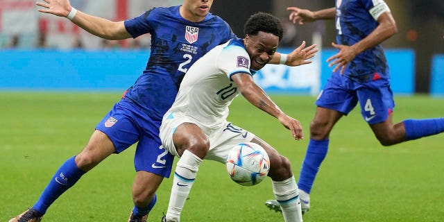 Sergino Dest of the United States, left, challenges for the ball with England's Raheem Sterling during the World Cup group B soccer match between England and The United States, at the Al Bayt Stadium in Al Khor, Qatar, Friday, Nov. 25, 2022.