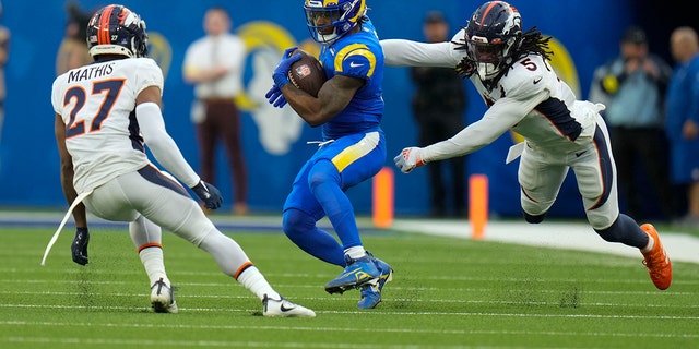 The Los Angeles Rams run between Denver Broncos cornerback Damari Mathis, left, and linebacker Randy Gregory during the first half of an NFL football game between the Los Angeles Rams and the Denver Broncos in Inglewood on Sunday, December 25, 2022. Running Back Come Akers, California. 