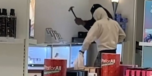 Robbers using sledgehammers to smash a display case. 