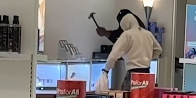 Robbers using sledgehammers to smash a display case. 