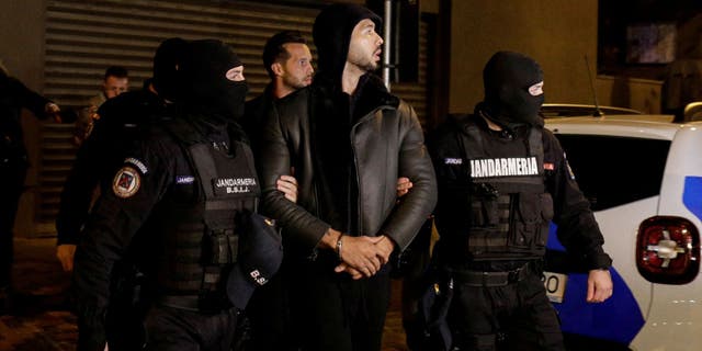 Andrew Tate and Tristan Tate are escorted by police officers outside the headquarters of the Directorate for Investigating Organized Crime and Terrorism in Bucharest after being detained for 24 hours in Bucharest, Romania, Dec. 29, 2022. 