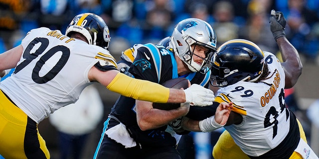 Carolina Panthers quarterback Sam Darnold is sacked by Pittsburgh Steelers linebacker T.J. Watt, left, and defensive tackle Larry Ogunjobi during the second half of an NFL football game between the Carolina Panthers and the Pittsburgh Steelers on Sunday, Dec. 18, 2022, in Charlotte, N.C.