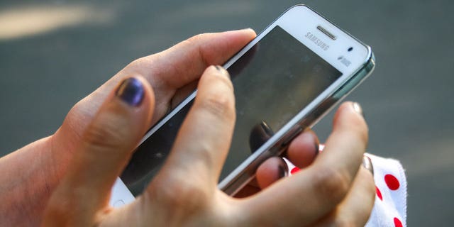 Photo of a woman holding a Samsung phone.