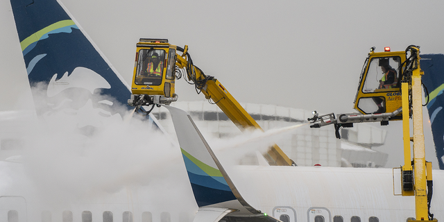 Workers deice an Alaska Airlines plane during a snow storm at Seattle-Tacoma International Airport in Seattle on Dec. 20, 2022.