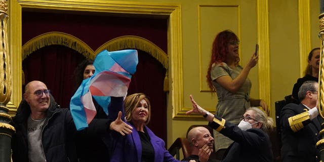 A security guard attempts to remove a transgender flag waved by activist Mar Cambrolle in the gallery following the voting session on the transgender rights bill at the Congress of Deputies in Madrid, Spain, on Thursday, Dec. 22, 2022. 