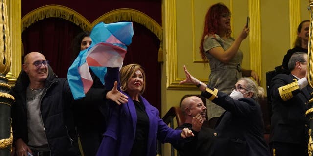 A security guard attempts to remove a transgender flag held up by activist Mar Cambrolle in the gallery after the voting session on the transgender rights bill at the Congress of Deputies in Madrid, Spain, Thursday, December 12. 22, 2022.