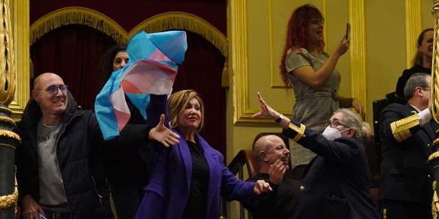 A security guard attempts to remove a transgender flag waved by activist Mar Cambrolle in the gallery following the voting session on the transgender rights bill at the Congress of Deputies in Madrid, Spain, on Thursday, Dec. 22, 2022. 