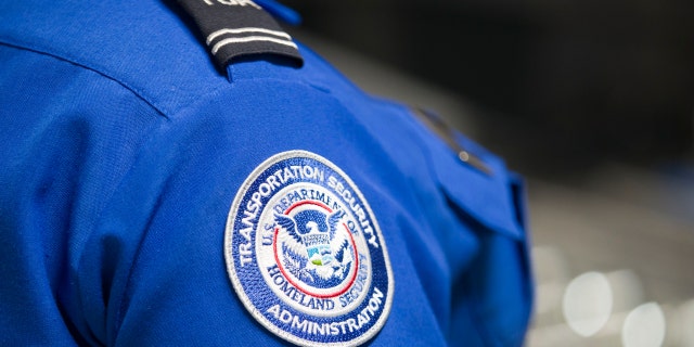 A Transportation Security Administration (TSA) agent's patch is seen as she helps travelers place their bags through the 3-D scanner at the Miami International Airport on May 21, 2019 in Miami, Florida.