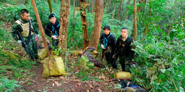 Thai soldiers stand with seized packages of illegal drugs and the body of a suspected smuggler at the scene of a gunfight a day earlier in Fang District in Chiang Mai, northern Thailand, Dec. 8, 2022.