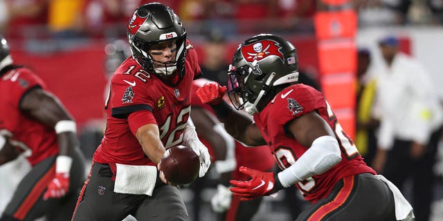 Tampa Bay Buccaneers quarterback Tom Brady, #12, hands off to running back Rachaad White in the first half of an NFL football game against the New Orleans Saints in Tampa, Florida, Monday, Dec. 5, 2022. 