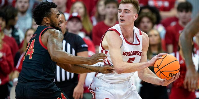 U-Tyler Wahl waseWisconsin, #5, ubukeka ephasa ibhola njengoba u-Donta Scott, #24, wase-Maryland, evikela engxenyeni yokuqala yomdlalo we-basketball wasekolishi le-NCAA ngoLwesibili, Disemba 6, 2022, eMadison, eWisconsin.