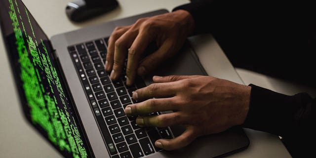 Photo of a man typing on a laptop.